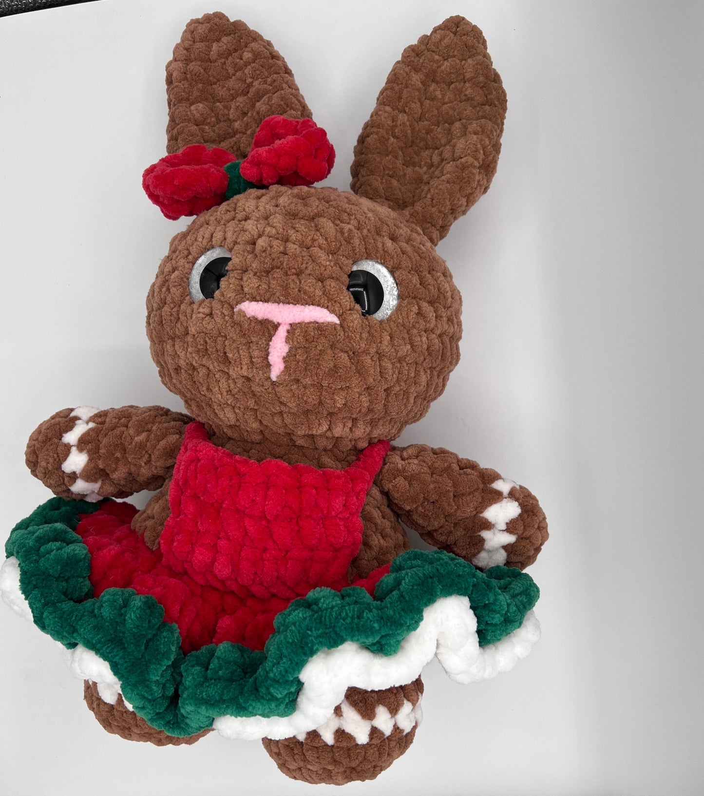 Handmade Christmas bunny plushie in brown with gingerbread-style dress, red bow, green ruffles, and white frosting trim