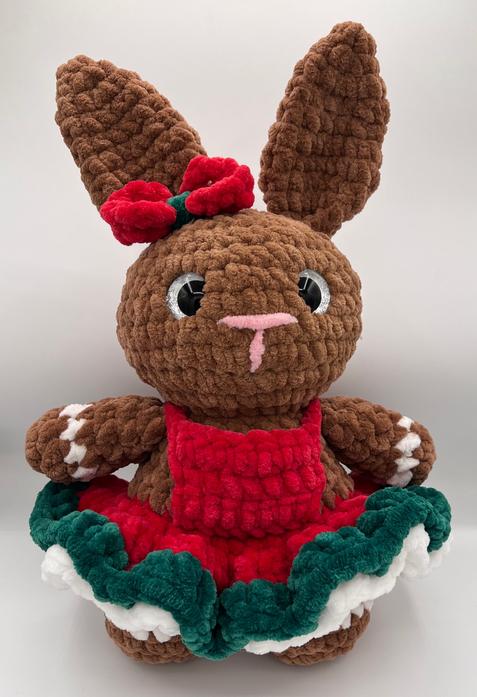 Full view of crochet bunny showing tall ears, pink nose, layered festive dress, and brown feet with white paw details