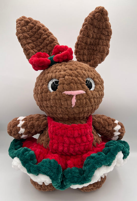 Full view of crochet bunny showing tall ears, pink nose, layered festive dress, and brown feet with white paw details